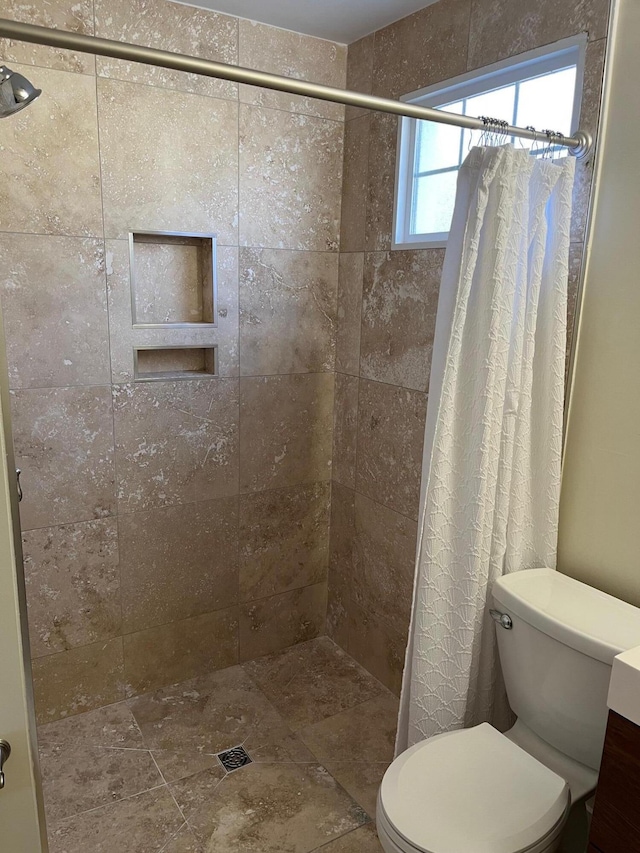 bathroom featuring tiled shower and toilet