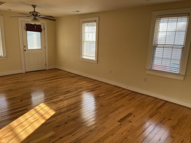 interior space with wood-type flooring, visible vents, ceiling fan, and baseboards