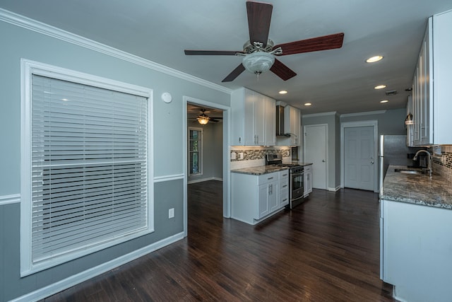 kitchen featuring dark wood-type flooring, white cabinets, stainless steel range with gas stovetop, decorative backsplash, and ceiling fan