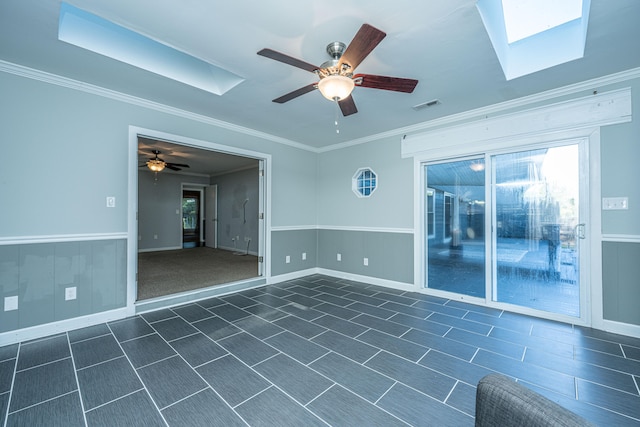 empty room with ceiling fan, a skylight, and ornamental molding