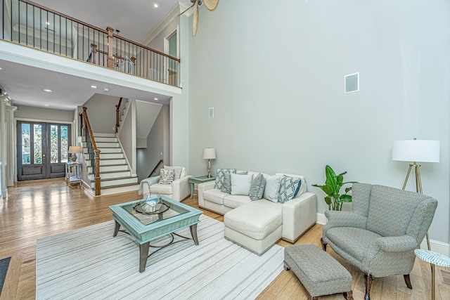 living room with ornamental molding, a high ceiling, and light wood-type flooring