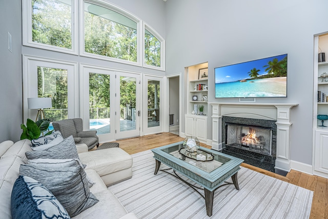 living room with a high end fireplace, a high ceiling, hardwood / wood-style flooring, and built in features