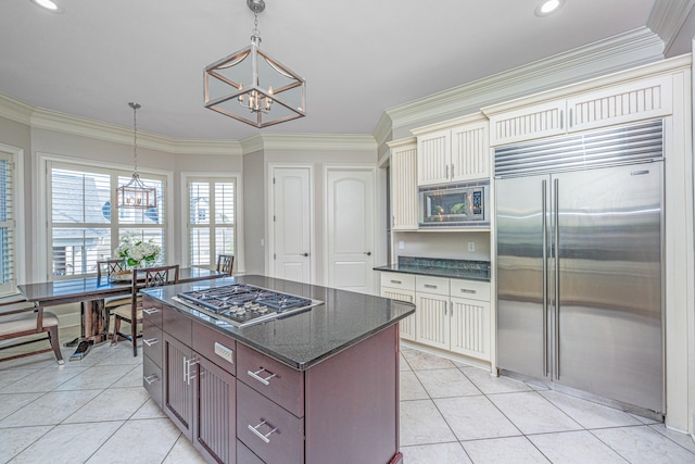 kitchen with cream cabinetry, decorative light fixtures, built in appliances, crown molding, and a notable chandelier