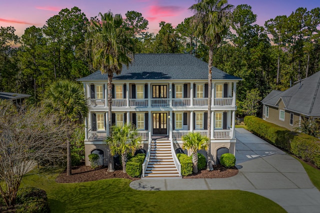 colonial inspired home featuring a yard, covered porch, and a balcony