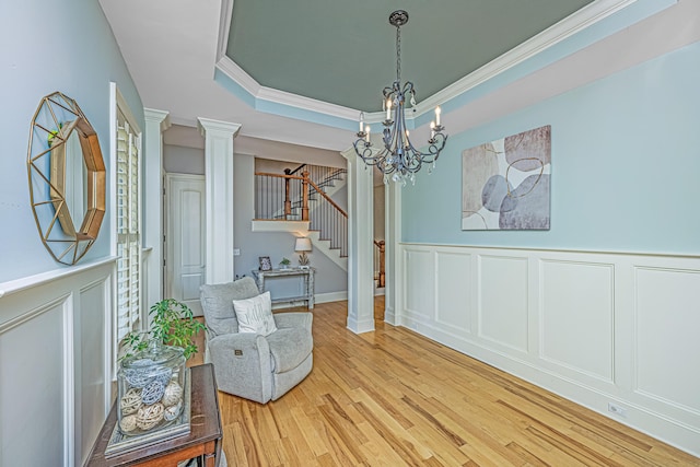 living area featuring decorative columns, a chandelier, and hardwood / wood-style floors