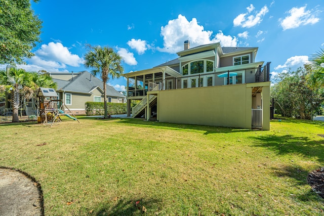 back of property with a playground and a yard