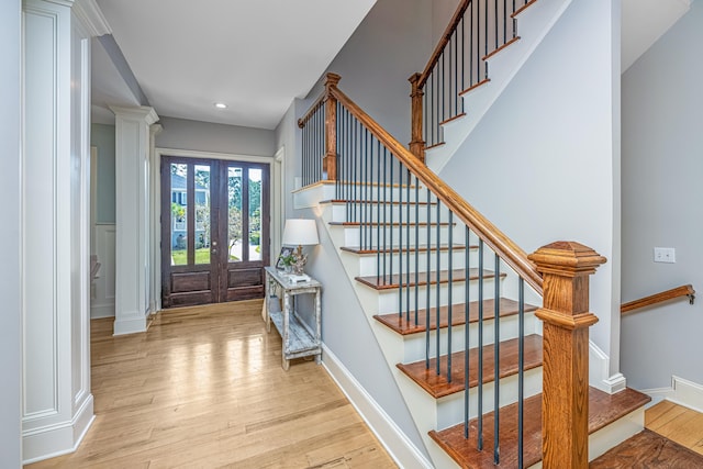 entrance foyer with french doors, ornate columns, and light wood-type flooring