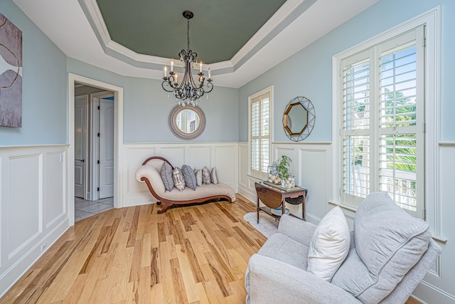 living area featuring a notable chandelier, a tray ceiling, and wood-type flooring