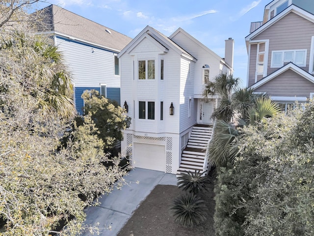 coastal home featuring stairway, an attached garage, and driveway