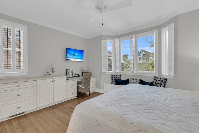 bedroom featuring light wood-type flooring, ceiling fan, crown molding, and built in study area