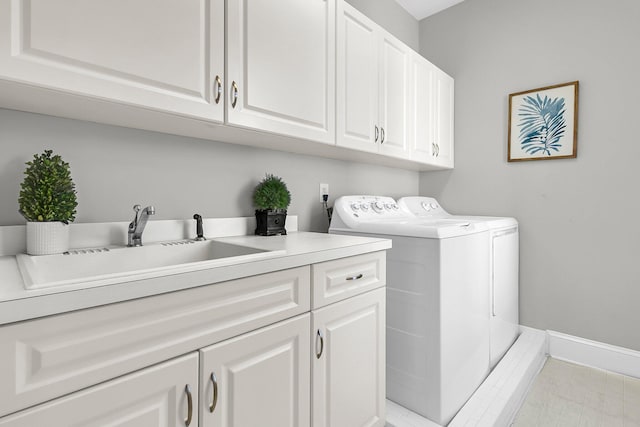 clothes washing area featuring separate washer and dryer, cabinet space, baseboards, and a sink