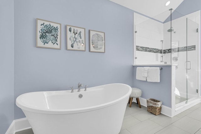 bathroom featuring tile patterned flooring, a shower stall, baseboards, and a freestanding bath