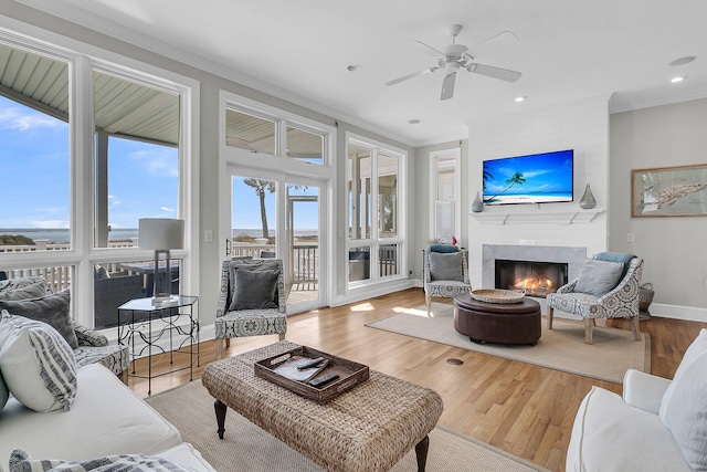 living room with baseboards, crown molding, a lit fireplace, and wood finished floors