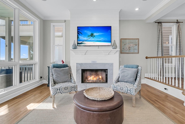 living area featuring a fireplace, crown molding, wood finished floors, and baseboards