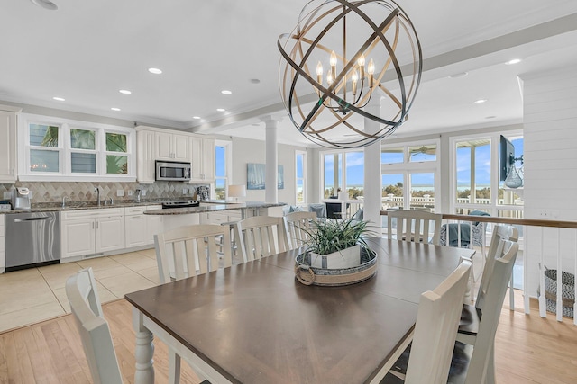 dining space featuring recessed lighting, crown molding, light wood-type flooring, and ornate columns