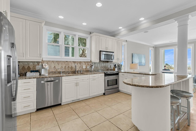 kitchen featuring a peninsula, white cabinets, backsplash, and stainless steel appliances