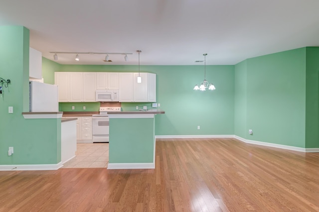 kitchen with a chandelier, hanging light fixtures, white appliances, light hardwood / wood-style floors, and white cabinets