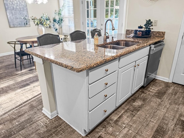 kitchen with sink, kitchen peninsula, stainless steel dishwasher, stone countertops, and white cabinetry