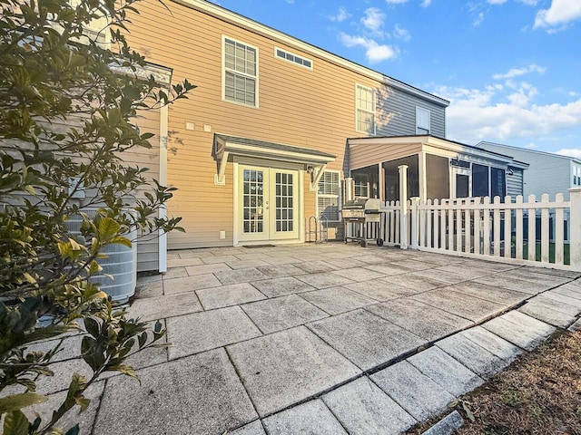 rear view of property with french doors, a patio, and a sunroom