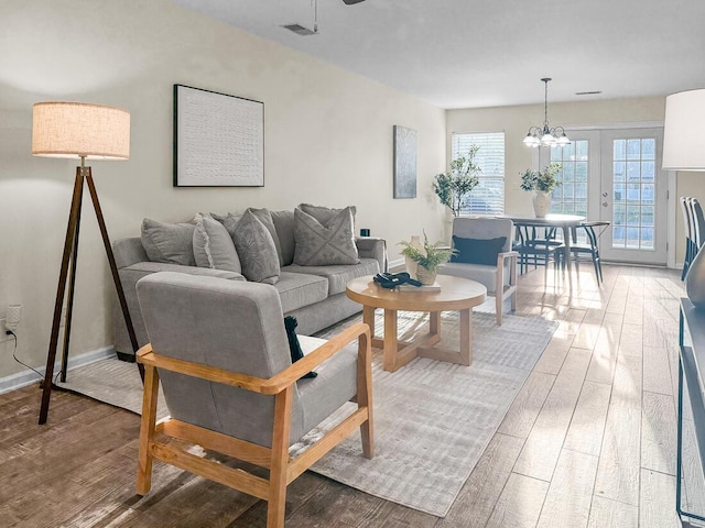 living room with french doors, an inviting chandelier, and hardwood / wood-style floors