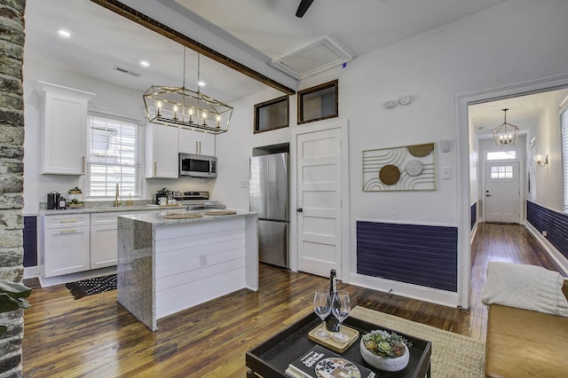 kitchen with stainless steel appliances, hanging light fixtures, light stone counters, dark hardwood / wood-style floors, and white cabinets