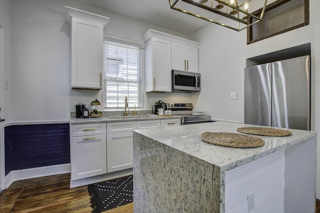 kitchen with sink, white cabinetry, light stone countertops, dark hardwood / wood-style flooring, and appliances with stainless steel finishes