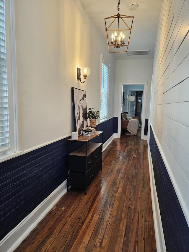 hallway with dark hardwood / wood-style flooring and an inviting chandelier