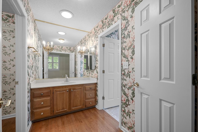9175 Spring Branch Ct, North Charleston, SC 29406 - bathroom featuring wallpapered walls, vanity, wood finished floors, a chandelier, and a textured ceiling