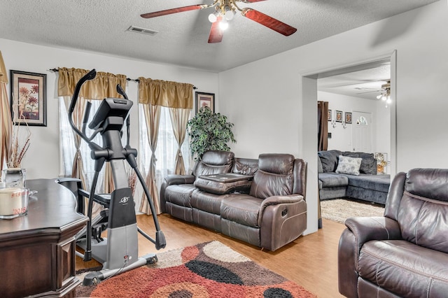 living room with ceiling fan, light hardwood / wood-style flooring, and a textured ceiling