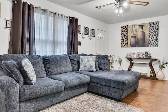 living room with ceiling fan, wood-type flooring, and a textured ceiling