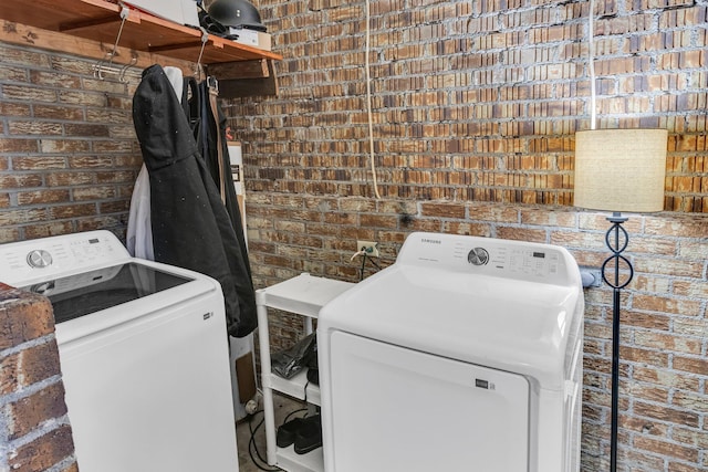 washroom with separate washer and dryer and brick wall