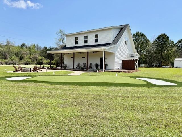 rear view of house with an area to practice putting, a patio, ceiling fan, and a yard