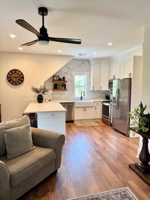 kitchen with stainless steel appliances, a peninsula, ceiling fan, white cabinetry, and recessed lighting