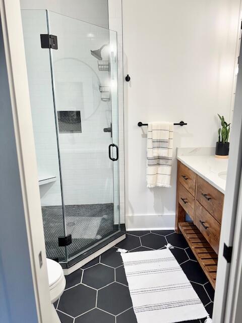 full bath with vanity, a stall shower, toilet, and tile patterned flooring