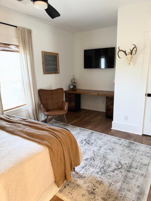 bedroom with wood finished floors, a desk, a ceiling fan, and baseboards