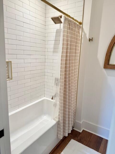 full bath featuring wood finished floors, shower / tub combo with curtain, and baseboards