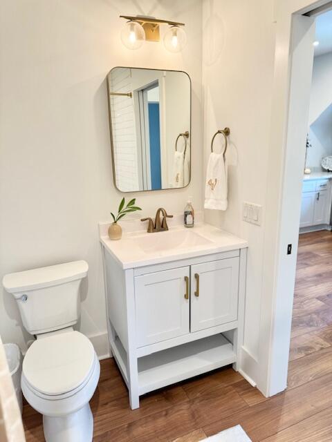 bathroom featuring wood finished floors, vanity, toilet, and baseboards