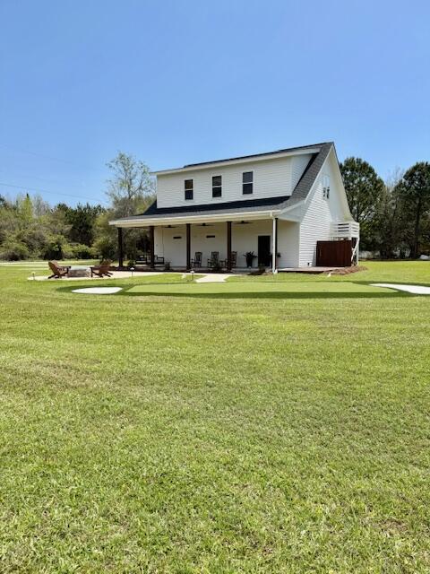 back of property with a ceiling fan and a yard
