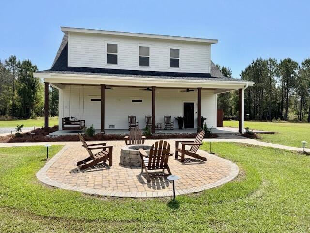 rear view of house featuring a ceiling fan, a patio area, a fire pit, and a yard