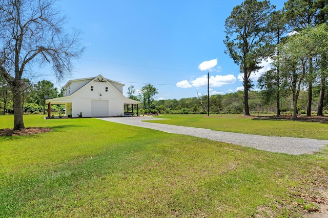 view of green lawn featuring gravel driveway and a detached garage