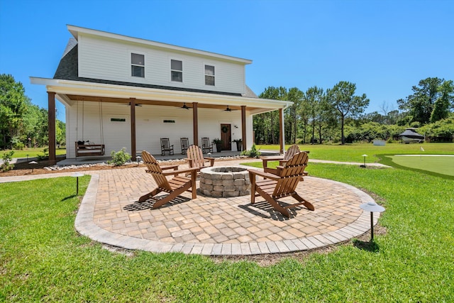 rear view of property featuring a putting green, an outdoor fire pit, ceiling fan, a patio area, and a lawn
