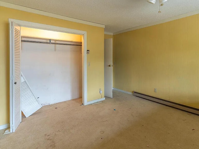 unfurnished bedroom featuring light carpet, a baseboard heating unit, a closet, and a textured ceiling