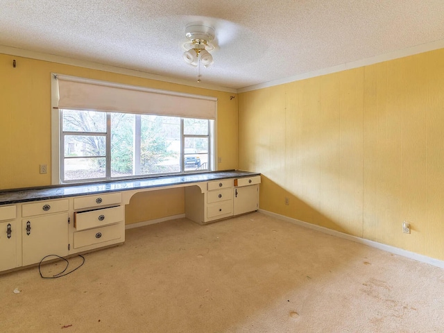 unfurnished office featuring built in desk, light colored carpet, and a textured ceiling