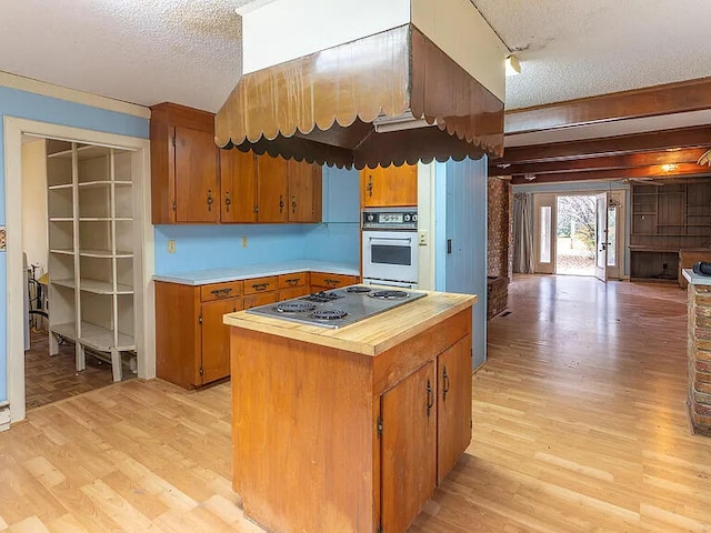 kitchen featuring rail lighting, cooktop, white oven, a textured ceiling, and light hardwood / wood-style flooring