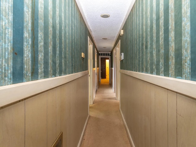 hallway featuring light carpet and a textured ceiling