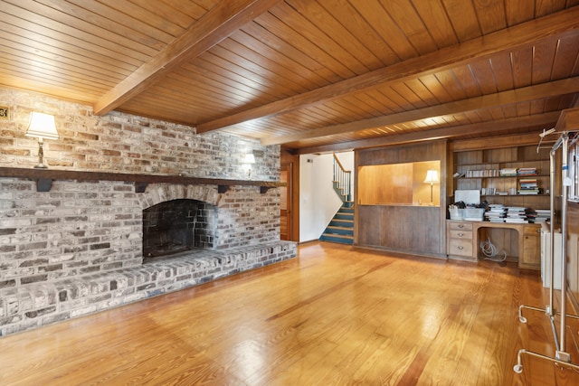 unfurnished living room featuring wooden ceiling, a brick fireplace, light hardwood / wood-style flooring, and beam ceiling