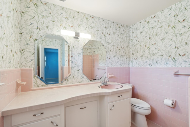 bathroom with vanity, toilet, and tile walls