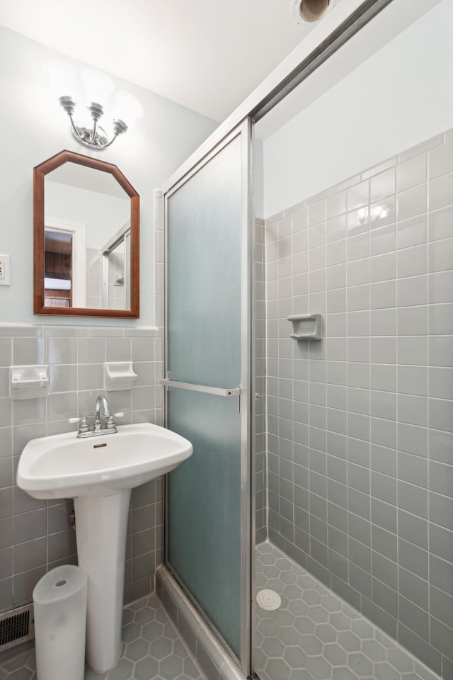 bathroom featuring a shower with door, tile patterned floors, sink, tile walls, and decorative backsplash