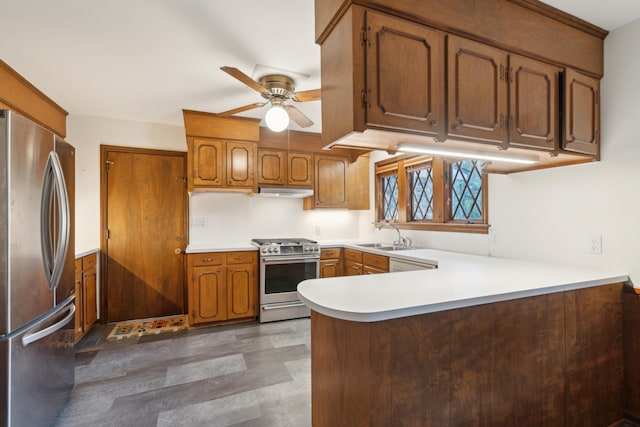 kitchen featuring stainless steel appliances, sink, dark hardwood / wood-style floors, kitchen peninsula, and ceiling fan