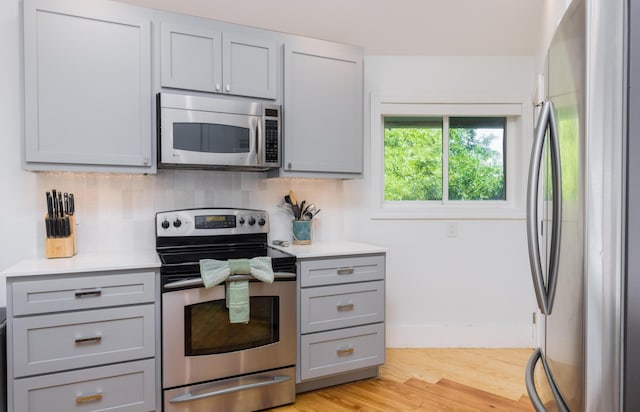 kitchen with light countertops, appliances with stainless steel finishes, gray cabinets, and decorative backsplash